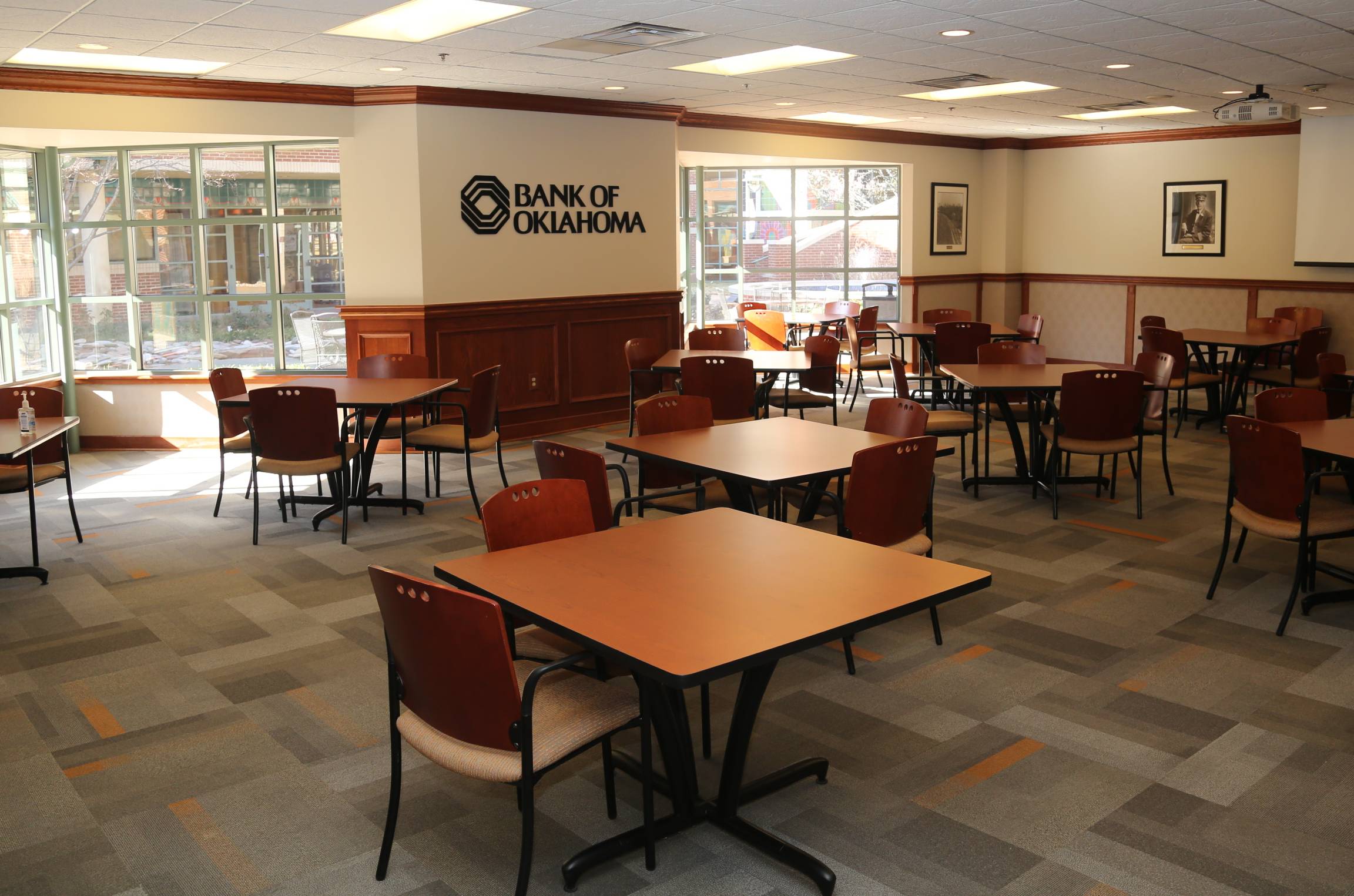 BOK room set up with empty square tables with four chairs per table.