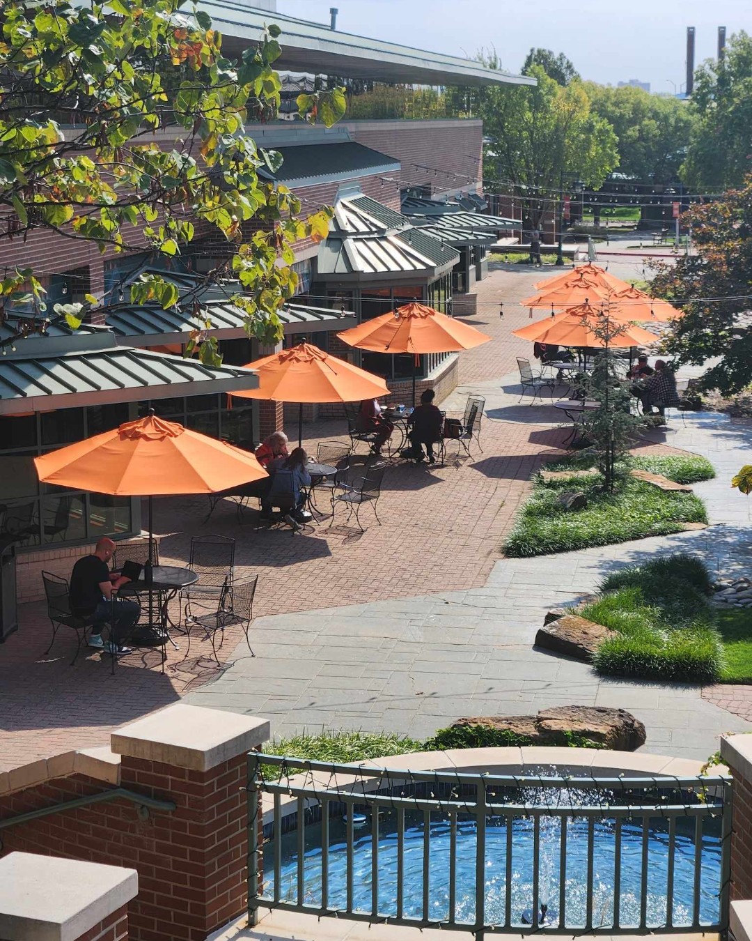 A row of tables with orange umbrellas on a sunny day in the courtyard between North Hall and Stanley E. White Hall