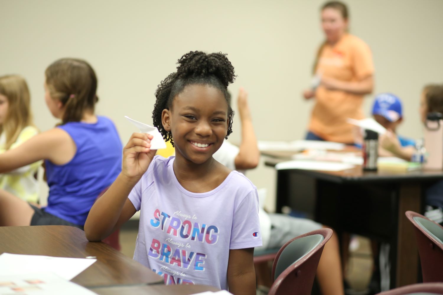 An Engineering Adventure camper shows her paper airplane