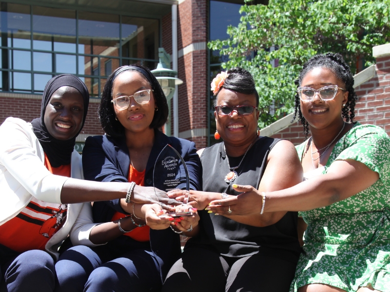 AASA Members hold award up while sitting outsidew in the courtyard