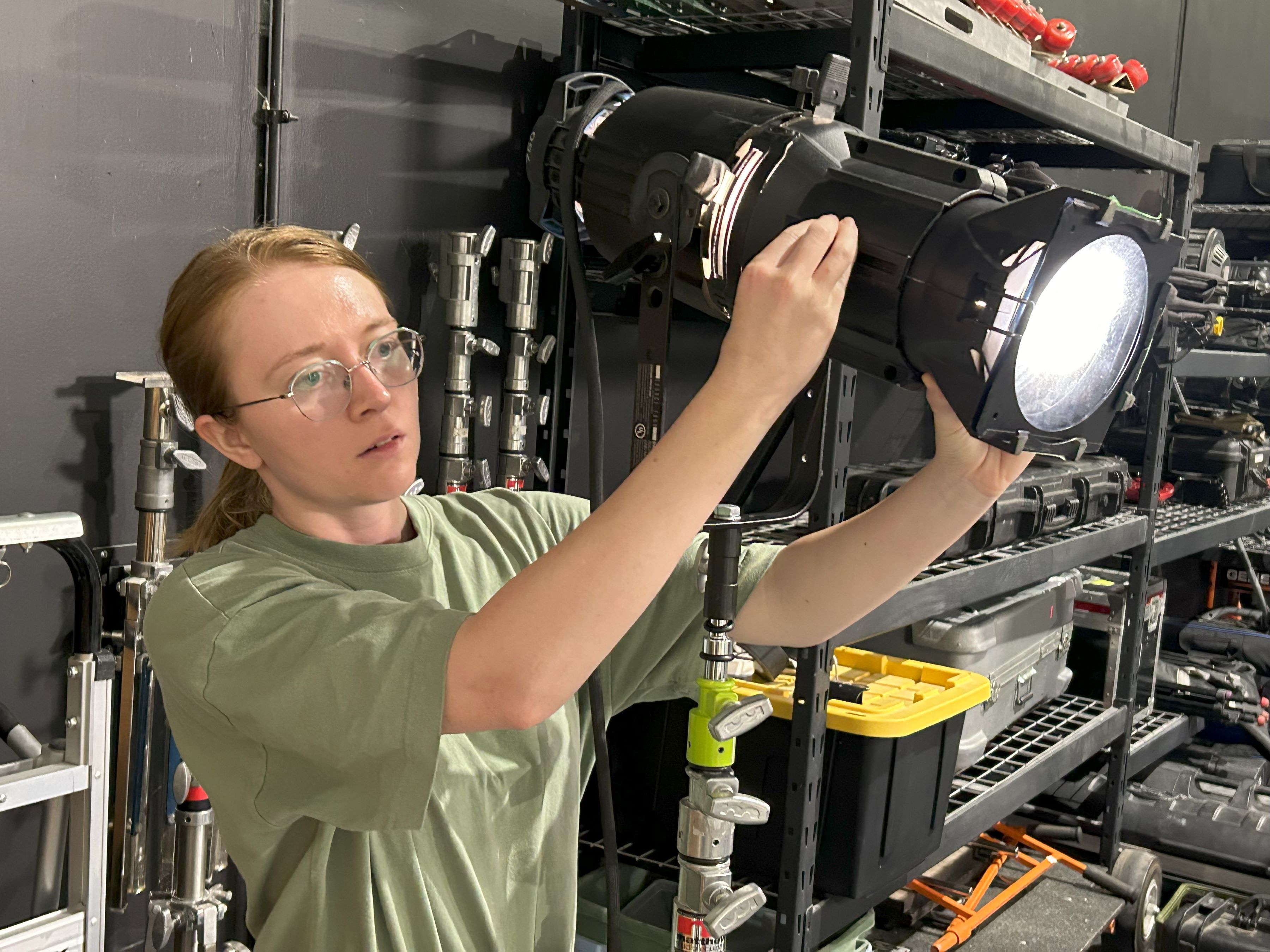 woman adjust light on film set