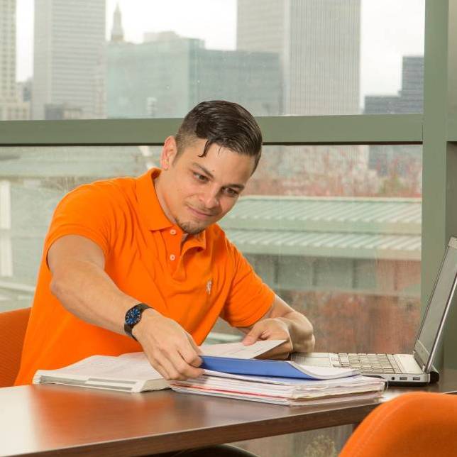 Man studying by a window with the Tulsa skyline in the background.