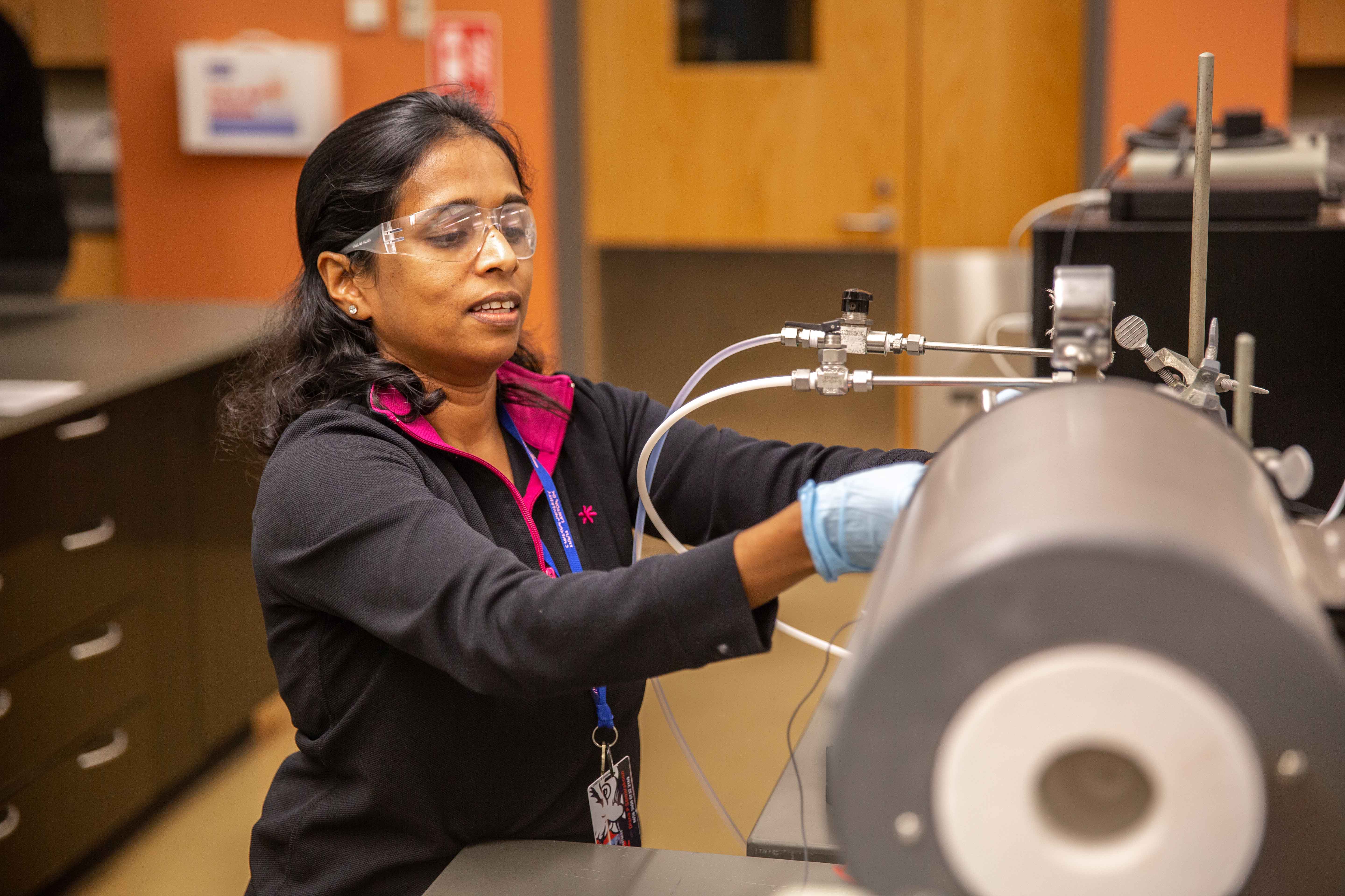 Woman working at a piece of materials characterization equipment.