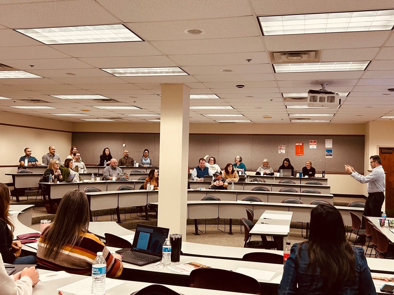 Professional development workshop taking place in a tiered classroom, with a male instructor standing at the front of the class