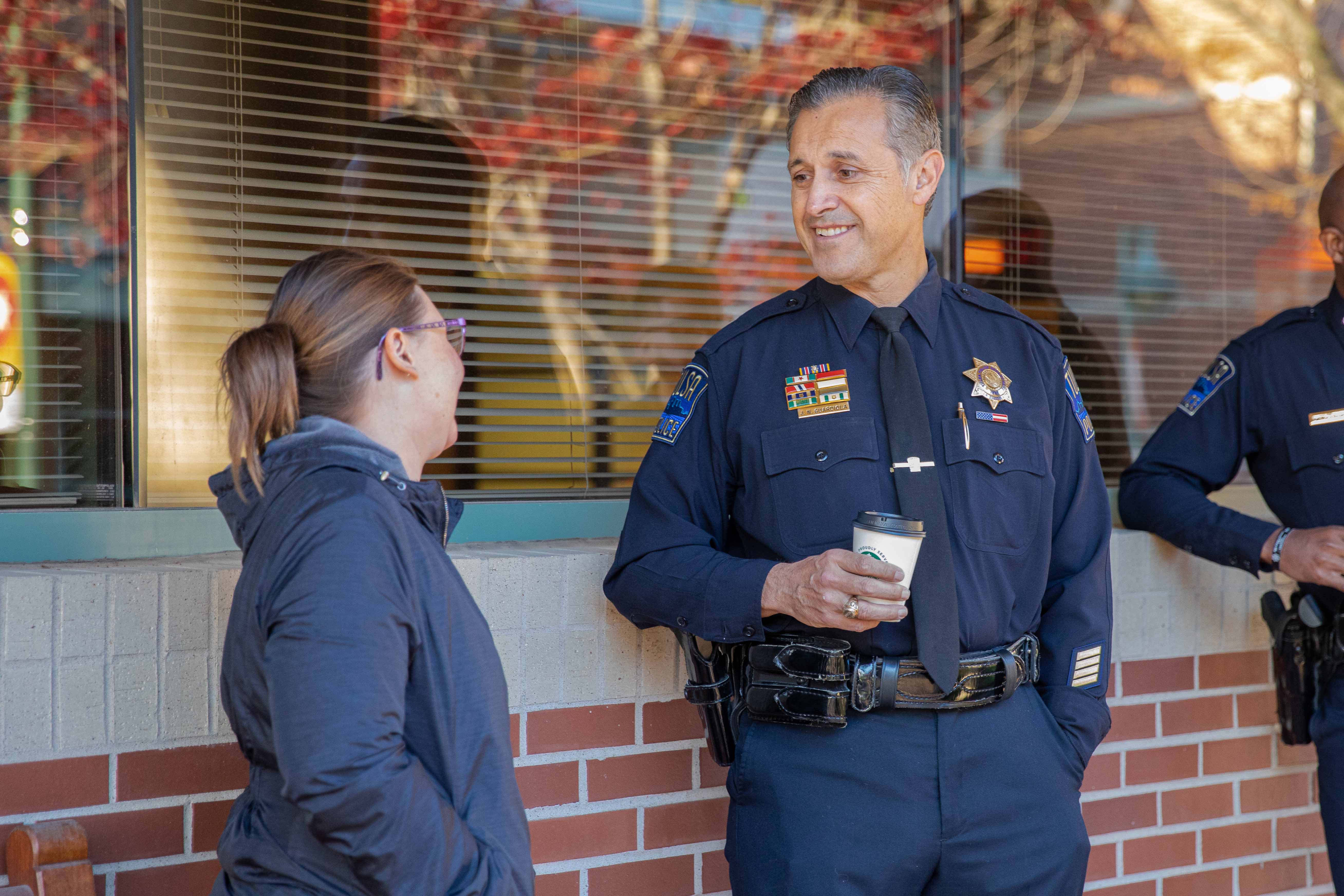 police officer talks to women outside of brick building