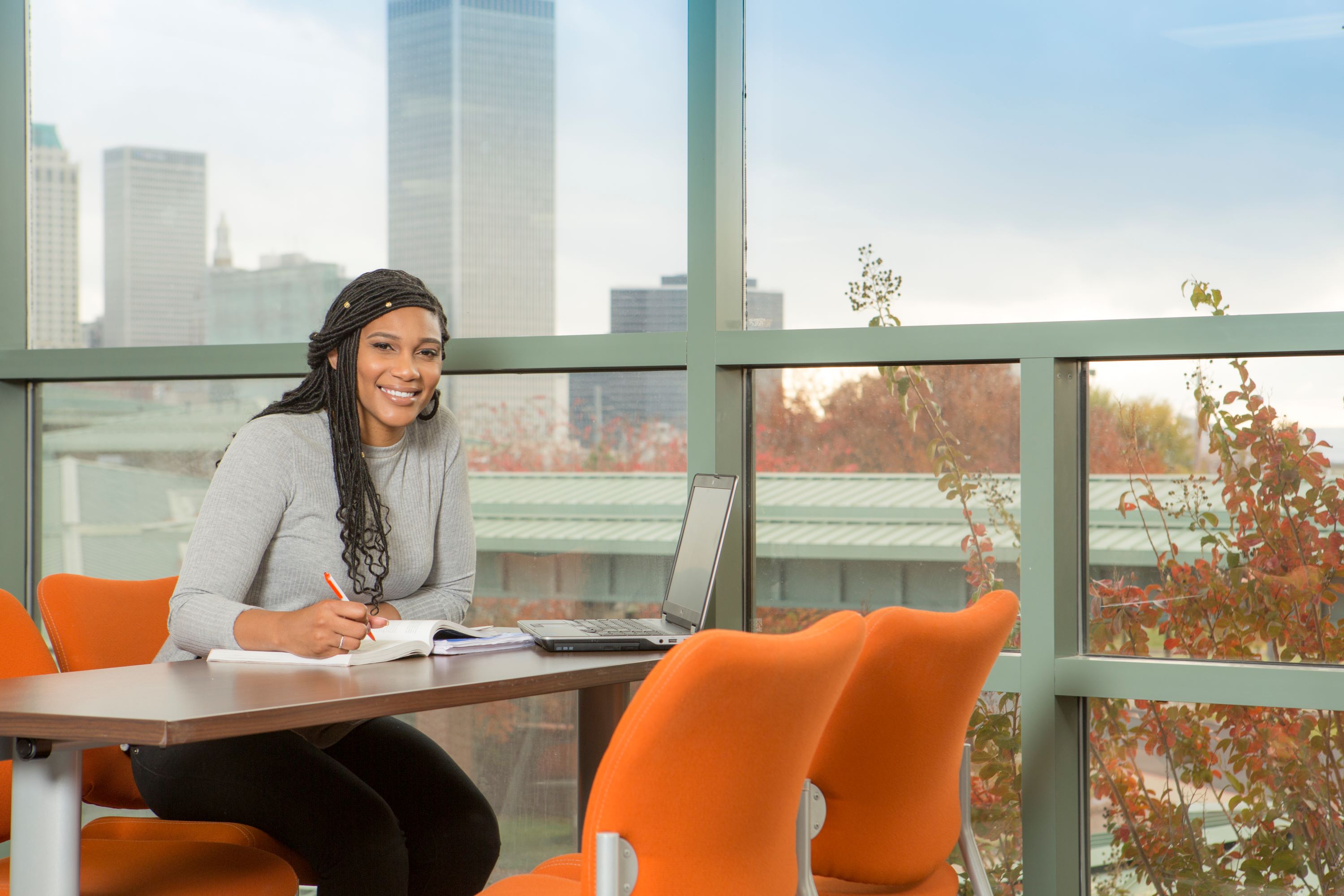 Woman working at table with skyline in background.